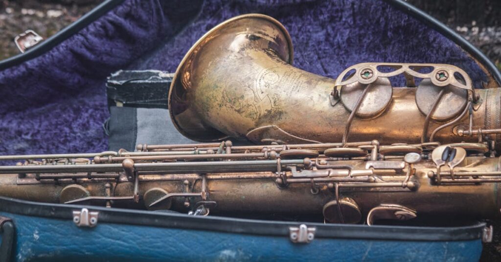 中古サックスの買取価格を確認する男性の後ろ姿。机には楽器と書類が並ぶ。